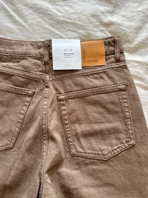 Bruna raka jeans från NA-KD - Säljer ett par bruna jeans från NA-KD med rak passform och hög midja. Aldrig använda 
