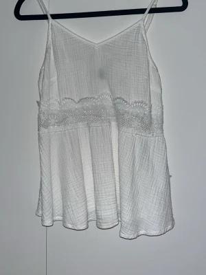 Vit linnetopp med spetsdetalj - Säljer en luftig vit topp med spets detalj.