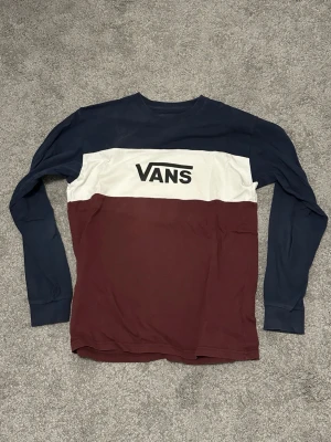 Vans långärmad tröja i blockfärger - Snygg långärmad tröja från Vans med blockfärger i marinblått, vitt och vinrött. Tröjan har rund halsringning och stort Vans-tryck över bröstet. Tillverkad i mjuk bomull för en skön känsla.