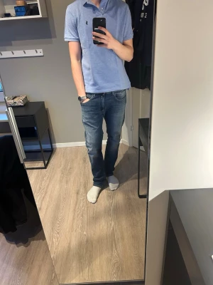 Ljusblå pikétröja från Polo Ralph Lauren - Säljer en ljusblå pikétröja från Polo Ralph Lauren med klassisk krage, knappar vid halsen och broderad logga på bröstet. Tröjan är kortärmad och har en normal passform. Perfekt till jeans eller shorts för en clean look. Väldigt bra skick använd ett par gånger väldigt snygg och perfekt till sommaren och våren. ⛱️☀️😎Piken är s men passar bra på 175 cm 