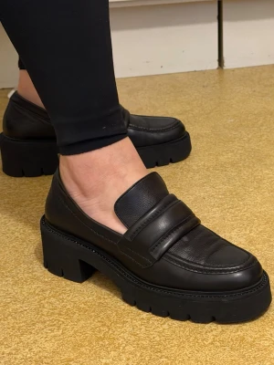 Chunky svarta loafers Kennel & Schmenger - Säljer ett par chunky svarta loafers från Kennel & Schmenger. Skorna är i äkta läder med kraftig sula och klassisk pennyloafers-design. Perfekta för dig som vill ha en edgy och trendig look med extra höjd.