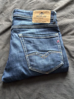 Blå jeans från Replay - Snygga blå jeans från Replay med klassisk femficksmodell och kontrastsömmar. Jeansen har en rak passform och är tillverkade i mjukt denimtyg. Märkeslapp i läder baktill och diskret logga på fickan framtill.