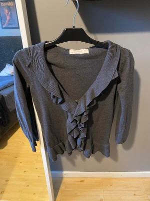 Stickad kofta - Säljer en fin grå stickad kofta med volanger från ZARA i storlek M. Har använts men är i gott skick.