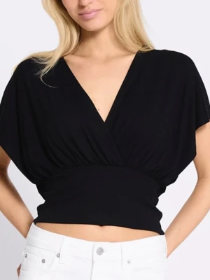 Svart omlottopp med v-ringning - Snygg svart omlottopp med djup v-ringning och bred midjeresår. Toppen är croppad och har korta, lösa ärmar. Perfekt att styla lager på lager eller bära som den är. Materialet känns mjukt och stretchigt.