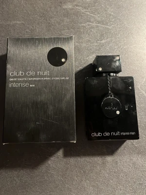 Club de Nuit Intense Man parfym - Club de Nuit Intense Man från Armaf. Sprejen är trasig men det kommer ut perfym från den fast i stora droppar. en parfym i en elegant, svart fyrkantig flaska med metalliska detaljer. Flaskan rymmer 105 ml och har en modern, maskulin design. Doften är känd för sin intensiva och fräscha karaktär, perfekt för dig som gillar att sticka ut.