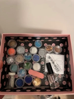 Nageldekorationer och glittermix - Säljer ett kit med nageldekorationer och glitter i flera färger som blått, guld, silver, grönt och orange. Innehåller små burkar med glitter, nagelfil, pensel, genomskinligt nagellack från City Color och dekorationspapper. Perfekt för kreativ nageldesign och nail art.