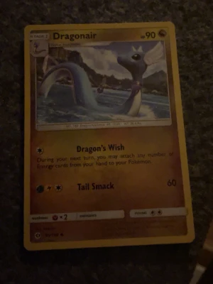 Dragonair Pokémonkort - Dragonair Pokémonkort med gul ram och färgglad illustration av Dragonair i vatten. Kortet har 90 HP och attacker som Dragon's Wish och Tail Smack. Text och symboler i svart och orange på framsidan, baksidan har klassisk blå Pokémon-design.