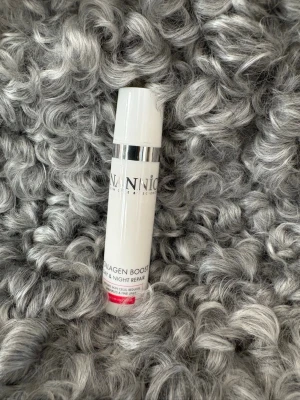 Nannic Collagen Boost Day & Night - Nannic Collagen Boost Day & Night Repair är en vit, cylinderformad pumpflaska med silverdetalj. Produkten är en ansiktskräm som boostar kollagen och passar för både dag och natt. Flaskan rymmer 15 ml och har en stilren design.