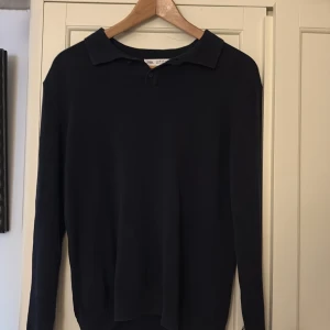 Mörkblå pikétröja  - Klassisk mörkblå pikétröja i storlek 164. Tröjan har lång ärm, krage och knäppning vid halsen. Tillverkad i ett väldigt mjukt material och den är väldigt stilig. Skick: 9,5/10✅🤩