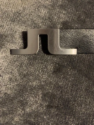 J.Lindeberg - Snyggt och stilrent svart bälte från J.Lindeber.Bältet är smalt och har en enkel metallspänne, perfekt för att lyfta vilken outfit som helst. Tillverkat i skinn för en klassisk look.