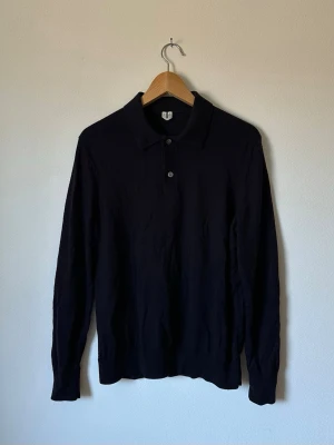 Mörkblå Arket långärmad pikétröja - Snygg mörkblå långärmad pikétröja med krage och två knappar framtill. Tröjan har en klassisk, stilren look och är tillverkad i ett mjukt, tunt material som passar perfekt till olika outfits. 6R10