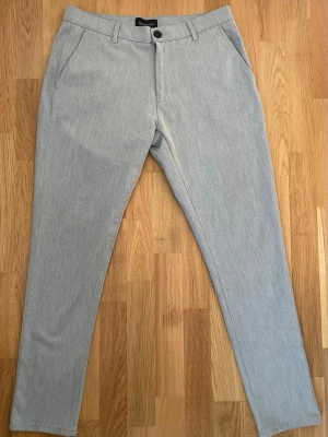 Tailored Originals kostymbyxor – W33/L32 – ljusgrå - Stilrena och moderna kostymbyxor från Tailored Originals i en ljusgrå nyans. Perfekta för både vardag och mer uppklädda tillfällen. Snygg slim/modern passform som funkar lika bra med sneakers som med skjorta.  ✔ Storlek: W33 / L32 ✔ Passform: Slim/modern fit ✔ Färg: Ljusgrå ✔ Skick: Bra skick, inga synliga defekter ✔ Detaljer: Sidofickor + bakfickor med knapp  Passar perfekt till jobb, fest eller en clean vardagslook.