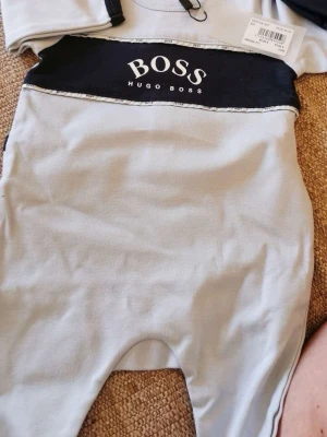 Grå bodyset från Hugo Boss - babyblå Hugoboss pyjamas och mössa stl 0-3 månader. Helt ny i kartong perfekt som tex doppresent. Köpta för 99€
