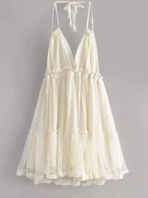 Krämvit klänning med volang - Söt krämvit kortklänning med tunna axelband som knyts i nacken och öppen rygg. Klänningen har volangdetaljer och lätt transparent lager i tyll. Perfekt för sommarens alla tillfällen!