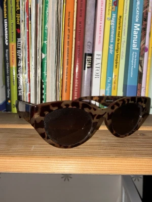 Bruna cat eye-solglasögon från Gina Tricot - Snygga solglasögon i klassisk cat eye-modell från Gina Tricot. Bågarna har ett trendigt sköldpaddsmönster i bruna toner och glasen är mörka. Perfekta för dig som vill ha en retrovibe och sticka ut lite extra. Tillverkade i plast.