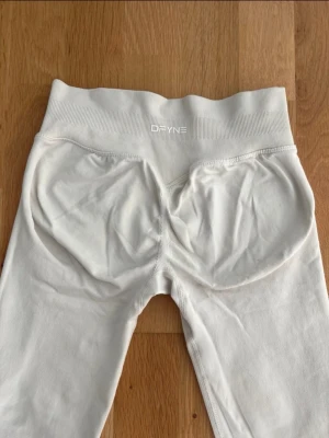 Vita DFYNE impact leggings  - Säljer ett par vita tränings leggings ifrån DFYNE i modellen ”impact.” Storlek M. Bra stretch, passar även mig som brukar ha S. Väldigt bra skick. Pris kan diskuteras. 