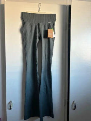 Ribbade leggings från Aim'n - Ribbade leggings från Aim'n i grå/grön färg. De har hög midja och stretchigt material som sitter tight och bekvämt. Perfekta för träning eller chill. Klassisk Aim'n-logga vid midjan och trendig ribbad struktur.