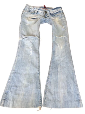 Vintage superlågmidjade ljusblå slitna bootcut jeans - Såå snygga vintage superlågmidjade ljusblå bootcut jeans med slitna detaljer och hål! ❤️Innebenslängd: 80 cm Midjemått: 39 cm 