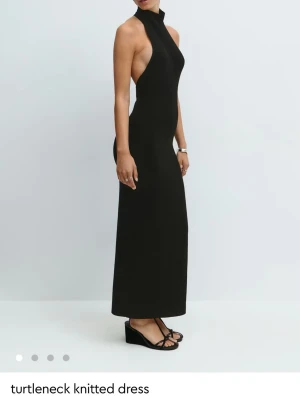 Svart stickad poloklänning från Gina - Snygg svart långklänning i stickat material med hög polokrage och djupa ärmhål. Figurnära passform som ger en stilren och modern look. Perfekt för dig som gillar minimalistisk stil och vill ha något trendigt och bekvämt.