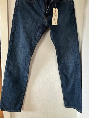 Grant jeans blå.  - Klassiska blå Grant jeans i rak modell med fem fickor och guldfärgade sömmar. Jeansen är tillverkade i slitstark denim och har en tidlös look som passar till det mesta. Perfekta för dig som gillar en enkel och clean stil. Storlek 32/32