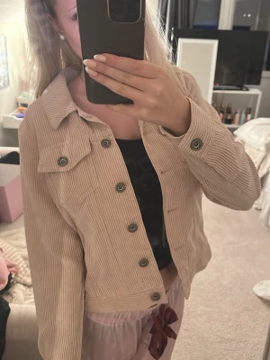 Beige corduroy jeansjacka - Säljer en beige jeansjacka i mjuk manchester med klassisk krage och knappstängning framtill. Jackan har en bröstficka med lock och silverfärgade knappar. Perfekt för dig som vill ha en trendig och avslappnad look.