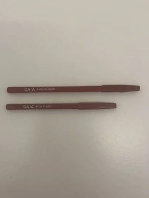 CAIA läppennor Frozen Berry & Pink Sunset - Två snygga läppennor från CAIA i nyanserna Frozen Berry och Pink Sunset. Båda pennorna har en smal, rund form och kommer med lock. Perfekta för att definiera och fylla i läpparna med en mjuk och krämig formula.