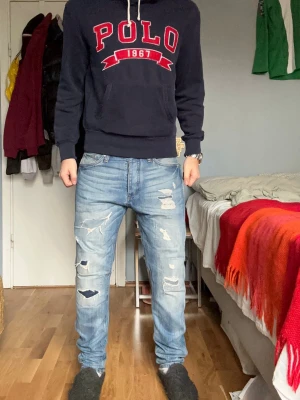 Blå slitna jeans från jack and jones  - Säljer ett par ljusblå jeans från jack and jones med flera slitningar och hål för en trendig, avslappnad look. Jeansen har klassisk femficksmodell, normal midja och raka ben. Perfekta för dig som gillar streetwear och en edgy stil.