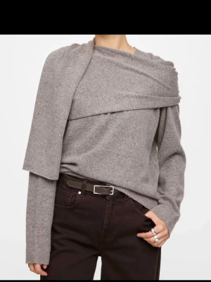 Grå /brun asymmetrisk stickad tröja bikbok storlek s  - Trendig grå/brun stickad tröja med asymmetrisk design och draperad detalj över axeln. Tröjan har långa ärmar och en avslappnad passform. Perfekt för dig som gillar en unik och modern 