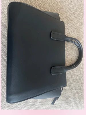 Svart stilren handväska i läderimitation - 💞Snygg svart stor handväska i läderimitation med två rejäla handtag och guldfärgade dragkedjor. Väskan har en strukturerad, fyrkantig form och minimalistisk design. Perfekt för dig som gillar klassisk och clean stil.💗Längd 24,5 cm bred 35 cm