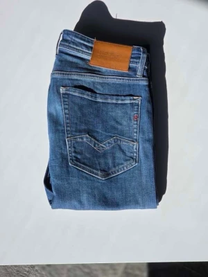 Blå jeans från Replay - Snygga blå jeans från Replay med klassisk femficksdesign och Jeansen har en läderpatch bak i midjan och Replay-logga på fickan fram. Perfekta för dig som gillar en avslappnad men trendig stil.