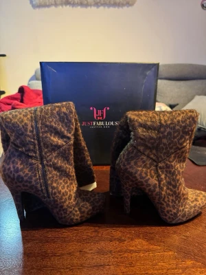 Leopardmönstrade stövletter JustFab - Snygga stövletter från JustFab med leopardmönster i bruna och svarta nyanser. Skorna har höga klackar och dragkedja på sidan. Materialet är mjukt tyg som ger en cool look. Perfekta för dig som vill sticka ut med ett djurmönster. Helt nya och aldrig använt. Utan prislapp. 
