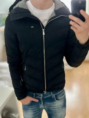 Svart pufferjacka från J.Lindeberg - Snygg svart pufferjacka från J.Lindeberg med quiltad design och huva. Storlek S/M, pris går självklart att diskuteras