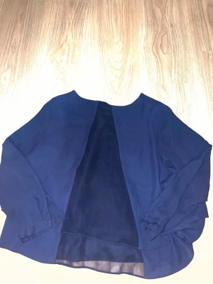 Mörkblå blus från Zara Basic - Stilren mörkblå blus från Zara Basic med rund halsringning och långa ärmar. Tillverkad i ett lätt, något transparent material som ger en luftig känsla. Perfekt att matcha med jeans eller kjol för en enkel men snygg look.
