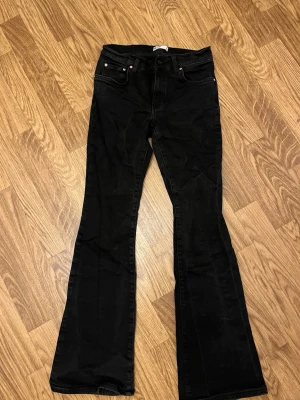 Svarta bootcut jeans - Säljer ett par svarta bootcut jeans med klassisk femficksmodell. Jeansen har utsvängda ben och är tillverkade i ett mjukt denimtyg. Använda fåtal gånger