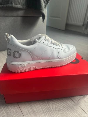 Turkosa sneakers från Hugo - Stilrena turkosa sneakers från Hugo i läder med klassisk låg siluett. Skorna har tydlig logga på hälen och på sulan, samt perforerade detaljer framtill. Snygga snörningar och diskret branding på plösen. Perfekta för en clean och modern look.