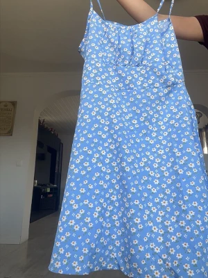 Blå blommig sommarklänning - Söt blå klänning med vita och gula blommor, smala axelband och lätt utställd passform. Perfekt för varma dagar och har en luftig känsla. Klänningen är ärmlös och har en klassisk somrig look💕Kolla in min profil för fler fina och trendiga plagg!