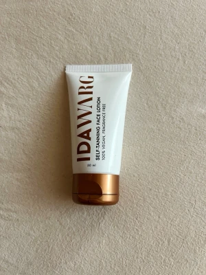IDA WARG Self-Tanning Face Lotion - Säljer en Self-Tanning Face Lotion från IDA WARG. Tuben är vit med bronsfärgat lock och rymmer 50 ml. Produkten är 100% vegansk och doftfri, perfekt för dig som vill ha en naturlig solkysst look utan parfym. Enkel att applicera och passar alla hudtyper. Endast testad en gång.