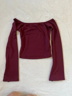 Vinröd offshoulder topp - vinröd offshoulder topp/långermad med långa ärmar och slits vid ärmsluten. Toppen figurnära passform, på mig går den just bra över naveln. Storleken är xs.  Passar bra som festtopp men lika bra till skolan!🥰