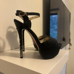 Klackskor Crape Myrtle - Säljer ett par svarta klackar från Crape myrtle ,höga klackar dekorerade med strass. Stått som dekoration senaste åren.