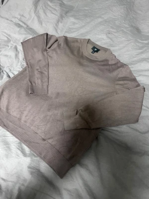 Beige Merinoull sweatshirt från H&M - En stilren beige sweatshirt från H&M i slim fit-modell. Tröjan har rund halsringning, långa ärmar och ribbade muddar vid ärmslut och nederkant. Perfekt för en avslappnad och trendig look.