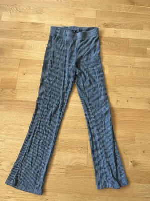 Grå ribbade byxor  - Grå ribbade byxor från Gina Tricot med utsvängda ben och hög midja. Mjukt och stretchigt material som sitter skönt.