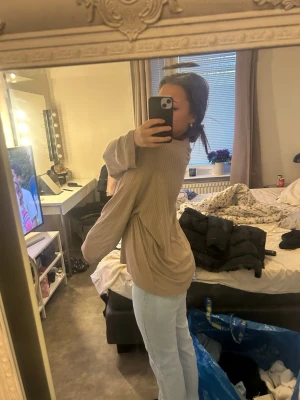 Beige oversized stickad tröja - Säljer en beige oversized stickad tröja med rund hals och långa, vida ärmar. Tröjan har en avslappnad passform och ribbad struktur som ger en trendig look. Perfekt att matcha med jeans för en chill stil.