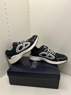 Svart vita diorr b30s - Snygga svarta sneakers från Diorr med vita snören. Skorna har en chunky vit sula och är tillverkade i mesh och syntetmaterial för en sportig vibe. Perfekta för dig som vill sticka ut med exklusiva och trendiga skor.