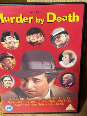 DVD Murder by Death - Säljer en DVD med filmen 'Murder by Death' av Neil Simon. Omslaget är rött med bilder på karaktärer och gul text. Filmen är en klassisk komedi-mysterium med kända skådespelare. Inkluderar specialfunktioner som intervju med Neil Simon.