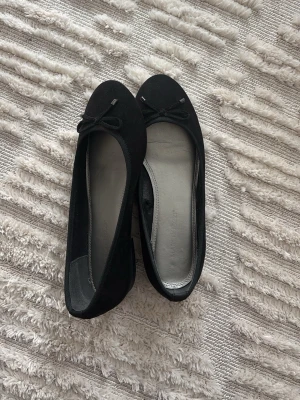 Svarta ballerinaskor med rosett - Klassiska svarta ballerinaskor med liten rosett framtill. Perfekta för en stilren och enkel look. Säljer eftersom de var för stora för mig 