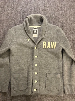 Grå kofta från G-Star RAW - Sjukt eftertraktad G-Star RAW kofta i grå – stl M. Stilren och populär modell som är svår att få tag på, särskilt i denna färg och i fint skick. • Storlek: M • Skick: Fint skick • Färg: Grå Kan även gå ner lite i pris vid snabb affär! 