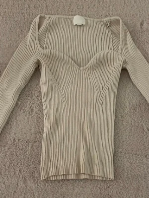 Ribbad beige topp från H&M - Säljer en superfin beige ribbad topp. Perfekt för hösten och våren. Bara använt ca 2 gånger.