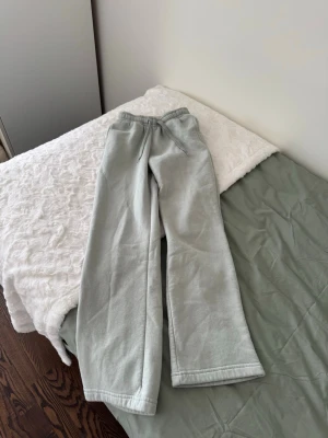Ljusgrön mjukis set med vida ben - Säljer ett  ljusgrön mjukis set med vida ben och resår i midjan. Byxorna har dragsko och sidofickor, perfekta för chill dagar hemma eller när du vill vara bekväm. Materialet är mjukt och skönt, troligtvis bomull eller bomullsblandning. Byxan är storlek xxs och tröjan xs 