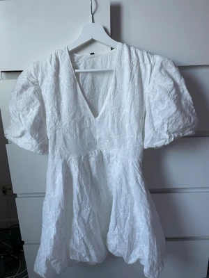 Vit kortklänning med puffärm - Supersöt vit kortklänning med puffiga kortärmar och v-ringning. Perfekt för sommarens alla tillfällen, studenten och även skolavslutning💗säljes på grund av att jag hittat en annan klänning till studenten