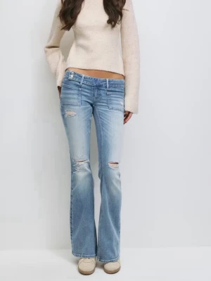 Ljusblå bootcut jeans med hål från Gina  - Snygga ljusblå bootcut jeans med håliga detaljer och hål på knäna. Jeansen har låg midja, klassiska fem fickor och är tillverkade i denim med stretch. Perfekta för en avslappnad och trendig look. Storlek 164 passar även xs